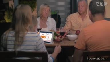晚上的户外家庭晚餐，父母和祖父母喝酒和<strong>吃饭</strong>，孩子看动画片